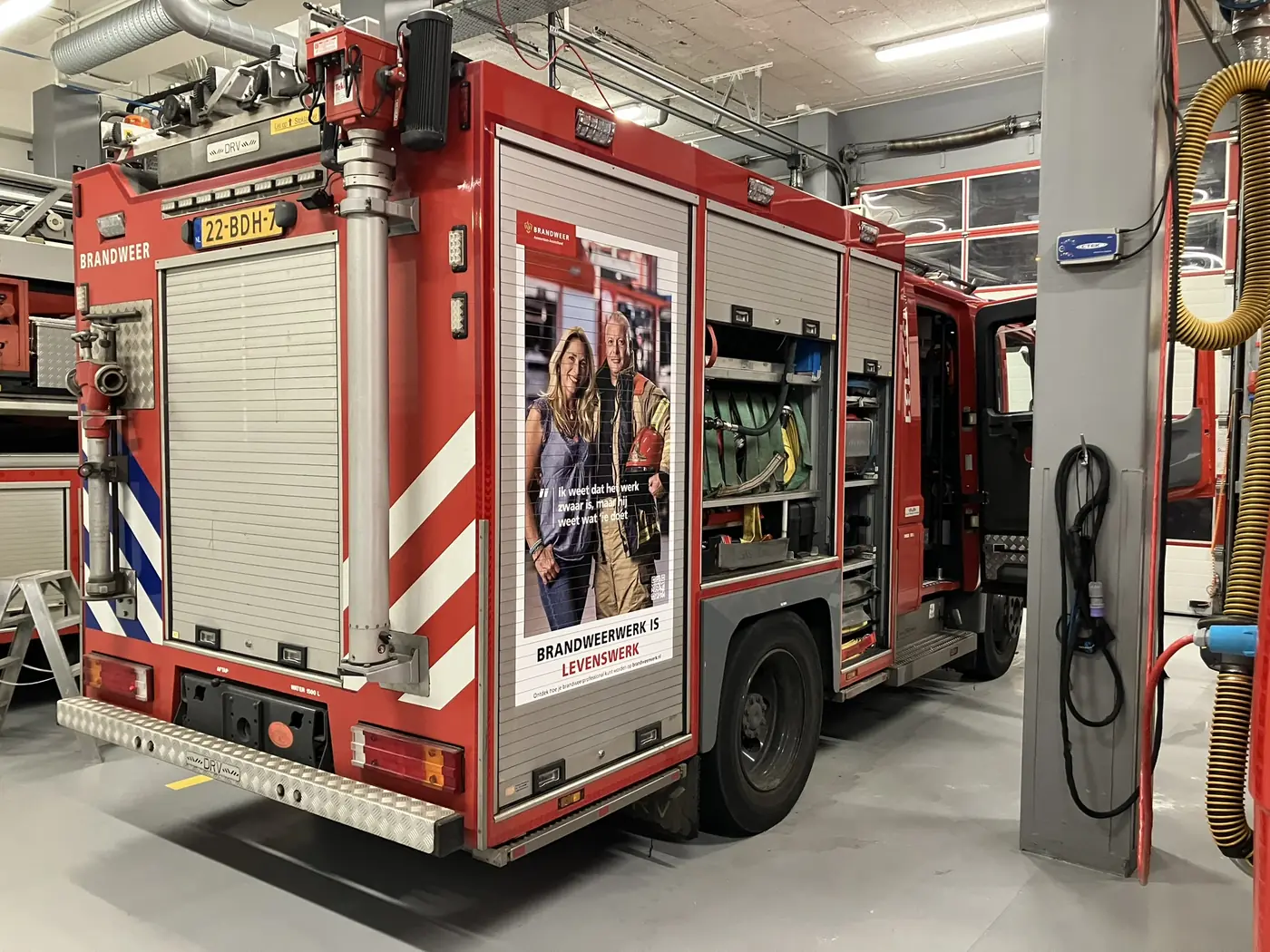 Promotieposter 'Brandweerwerk is levenswerk' gemonteerd op de achterzijde van een tankautospuit van Brandweer Amsterdam-Amstelland
